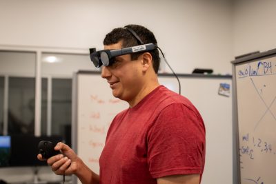 Brendan David-John wearing an eye-tracking device while holding the device's remote control.