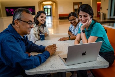 grad students and faculty around laptop smiling