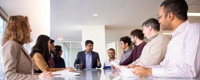Faculty member meets with a team of graduate students around a conference room table.